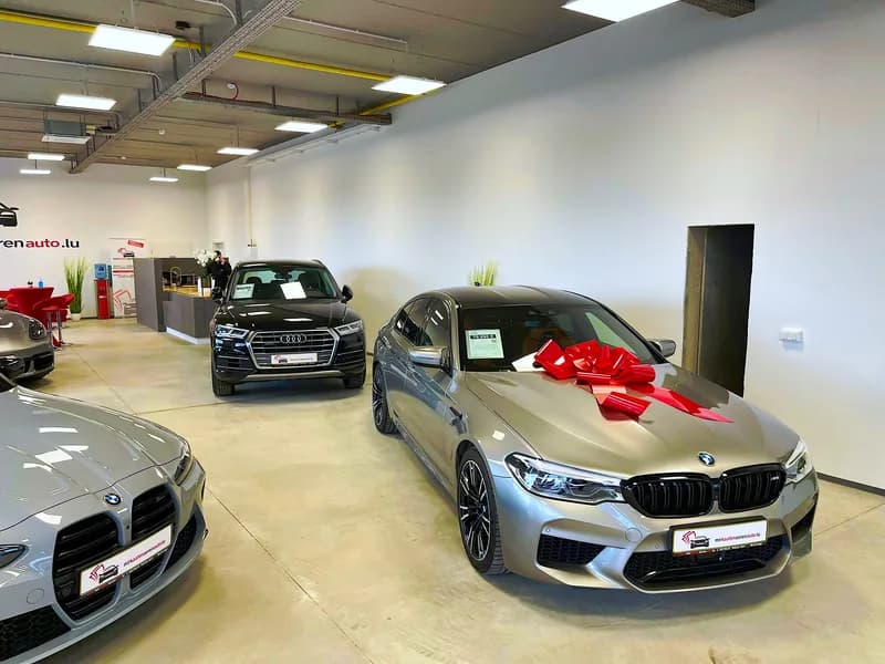 Erfolgreiche Fahrzeugübergabe bei MKAA - BMW M5 mit roter Schleife für zufriedenen Kunden