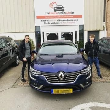 Zwei junge MKAA-Kunden mit ihrem dunkelblauen Renault Talisman vor der Filiale